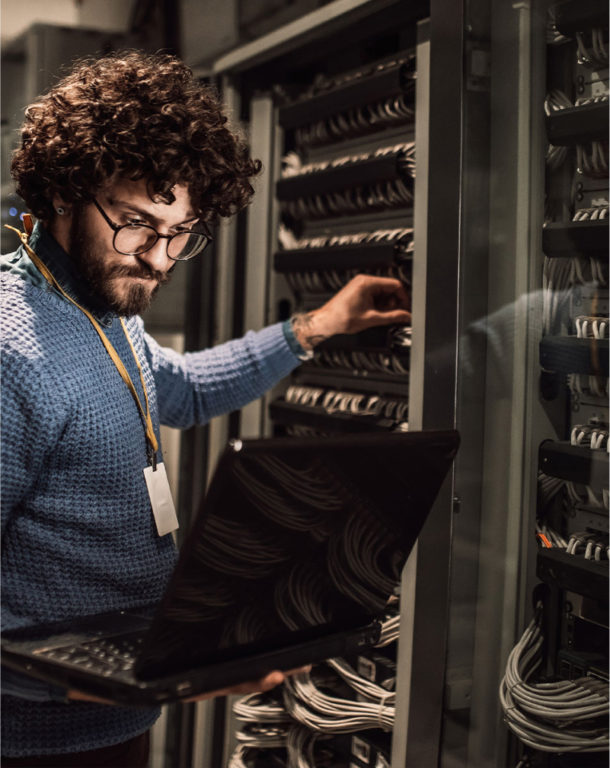 Man holding laptop in server room