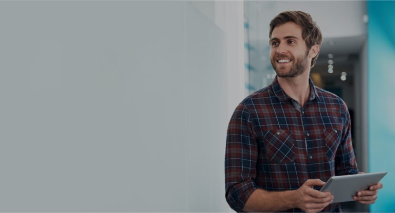 Man in plaid shirt smiling while holding tablet