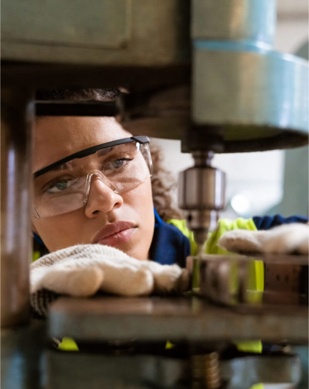 Female worker wearing safety gear operating machine in factory setting