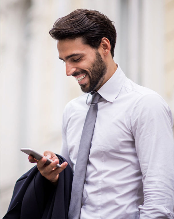 Man wearing tie smiling down at his cellphone
