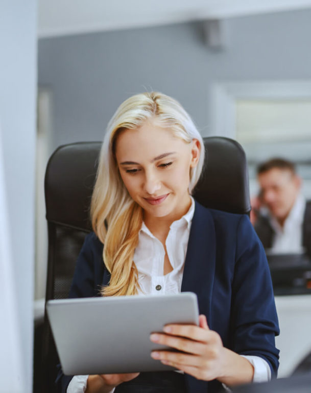 Woman working on a tablet sitting at a desk chair