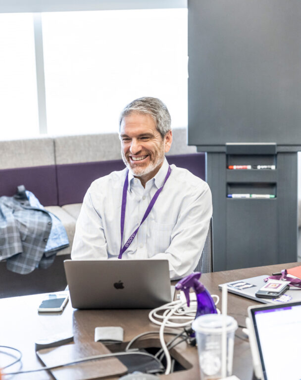 Ensono employee smiling at computer