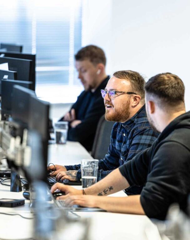 Three coworkers laughing at their desk