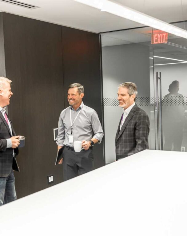 Three coworkers laughing into a conference room in ensono office