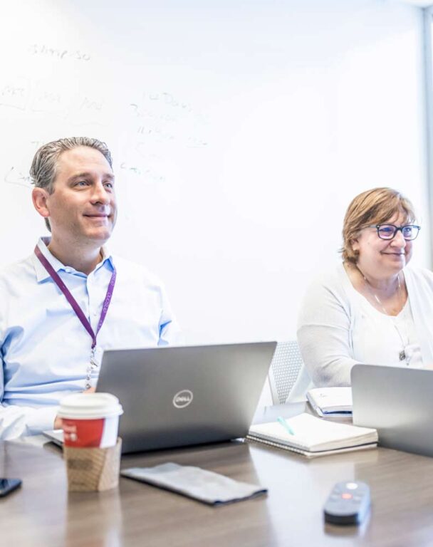 Two people working at laptops in a conference room