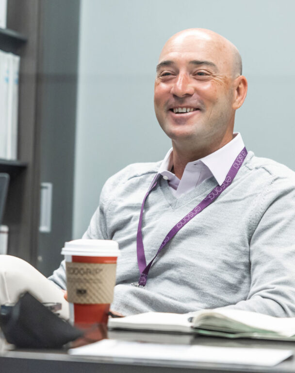 Ensono employee with lanyard on smiling at conference table