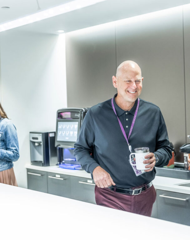 Employee smiling and walking in Ensono office