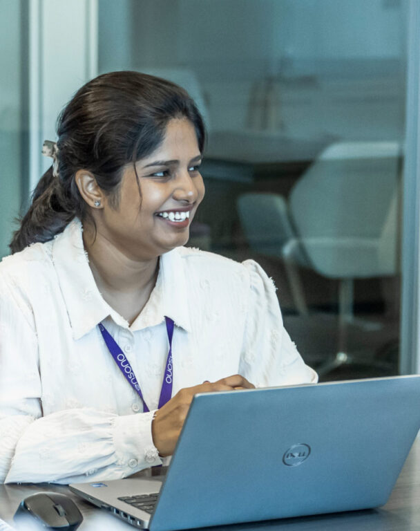 Ensono employee smiling and working on laptop