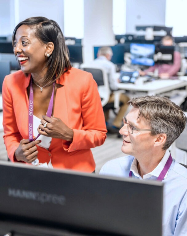 Ensono employees laughing in front of a computer