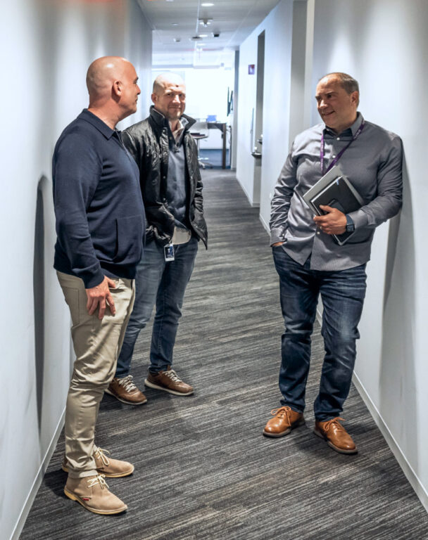 Three Ensono employees talking in an office hallway