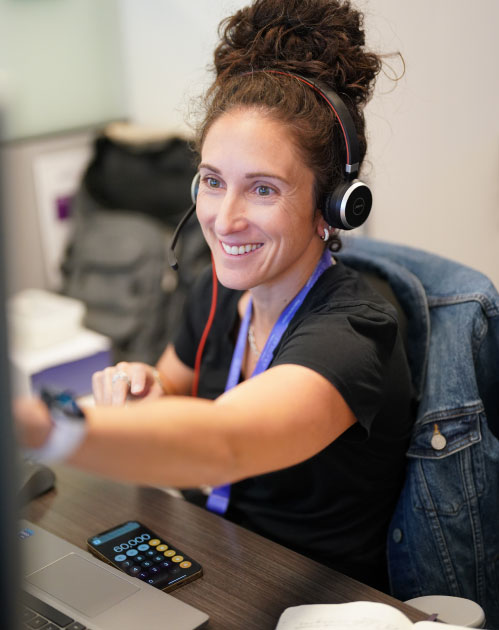 Female Ensono employee working on computer with headset
