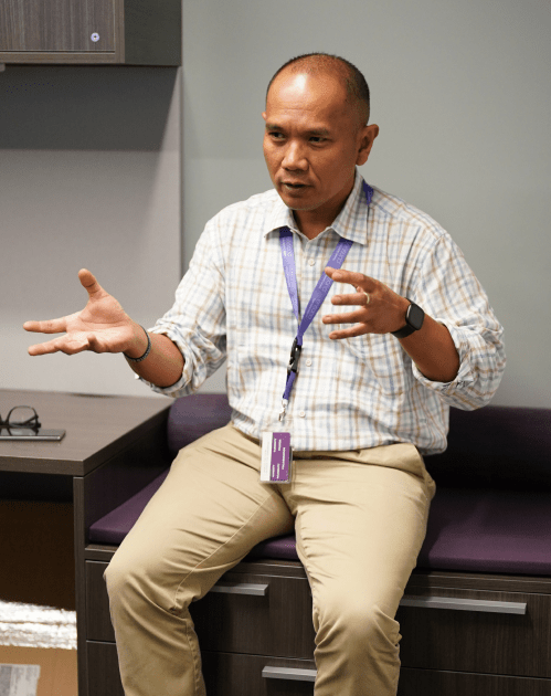 Ensono employee sitting on edge of desk talking