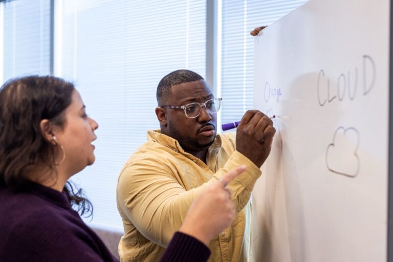 Two people discussing on the white board.